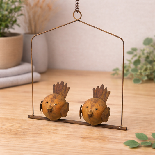 Metal bird swing garden ornament with two rustic birds on hanging frame styled on oak surface