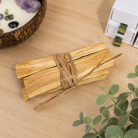 Natural Palo Santo wood sticks bundled together on a light oak surface, traditionally used for meditation, energy cleansing and spiritual wellbeing.